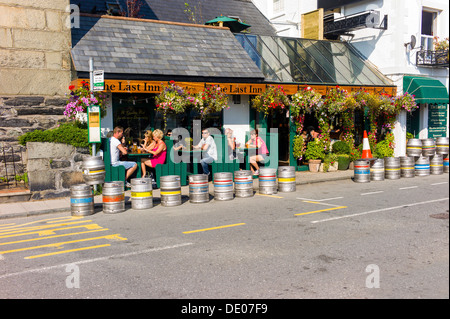 I clienti al di fuori seduta in una frequentata località public house di bere birre nel caldo sole, in primo piano un sacco di vuoto barili di birra Foto Stock