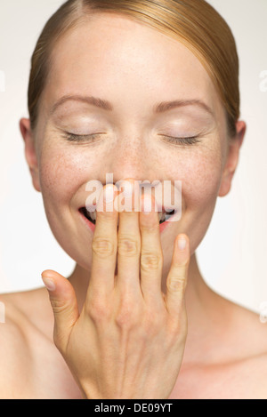 Giovane donna sorridente, che copre la bocca con la mano Foto Stock