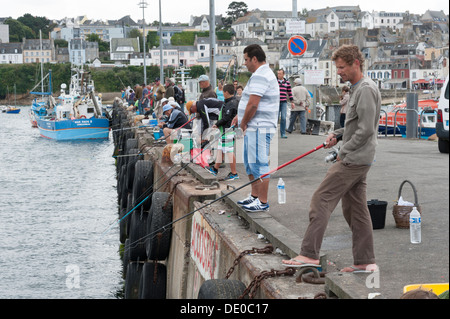 Un sacco di persone di pesca con asta e linea in corrispondenza della parete del porto a Douarnenez Bretagna Francia Foto Stock