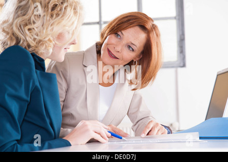 Manager che lavora in un ufficio con un tirocinante presso il computer Foto Stock