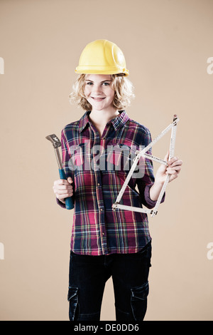 Ragazza con un martello e un righello di legno piegato nella forma di una casa Foto Stock