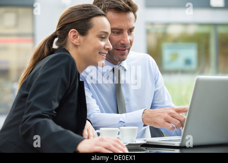 I soci dell'azienda lavorano insieme utilizzando il computer portatile all'aperto Foto Stock