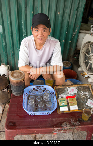 Il fumo di sigarette e tè vietnamita street proprietario di stallo ad Hanoi, Vietnam Foto Stock