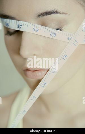 Donna con nastro di misurazione avvolto sulla faccia a occhi chiusi Foto Stock