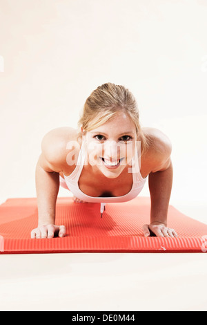 Giovane donna facendo push-up Foto Stock