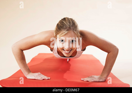 Giovane donna facendo push-up Foto Stock