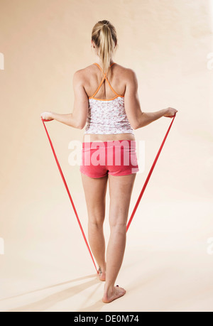 Giovane donna a fare gli esercizi con un con elastici Theraband Foto Stock