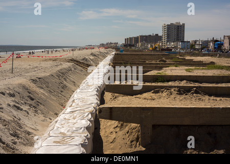 Il lavoro continua a ricostruire il Boardwalk danneggiato dall' uragano sabbioso nel Rockaway Beach Foto Stock