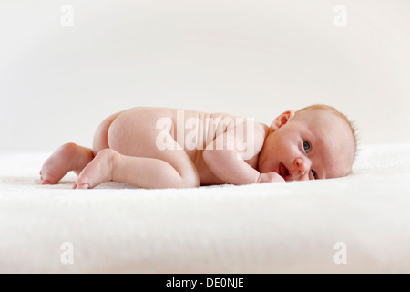 Baby girl, 3 mesi di età, giacente su una pelle di montone Foto Stock