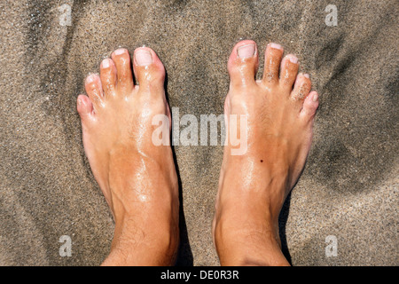 I piedi su una spiaggia, essendo lambite dal mare Foto Stock