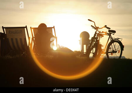Persona seduta su una sedia a sdraio, retro illuminato, in un parco pubblico a motivo dell'ex Berlino Tempelhof di Berlino Foto Stock