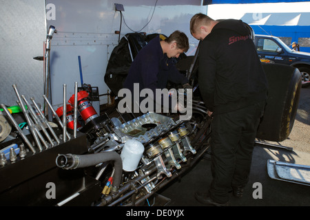 Meccanica a lavorare sul loro Ford Mustang Top Fuel Funny auto dragster dopo un motore di esplosione a Santa Pod box. Foto Stock