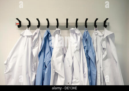 Indumenti da lavoro, bianco e blu camici da laboratorio su appendiabiti, laboratorio chimico Foto Stock