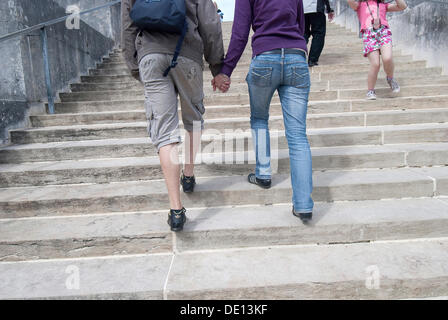 Coppia giovane salendo le scale insieme, mano nella mano, da dietro Foto Stock