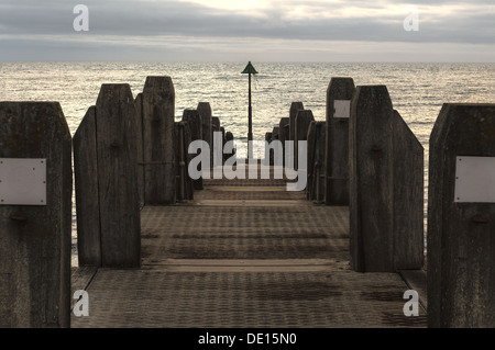 Vista verso i trend con orizzonte di riferimento e la fine del molo groyne con piattaforma Aberystwyth impostazione nascosto sun con luminosi nuvole retroilluminato Foto Stock