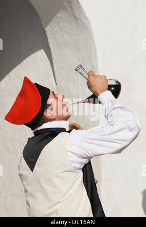 Giovane uomo in costume tradizionale di bere il vino al di fuori di un tipico spagnolo porron, Ibiza, Spagna, Europa Foto Stock