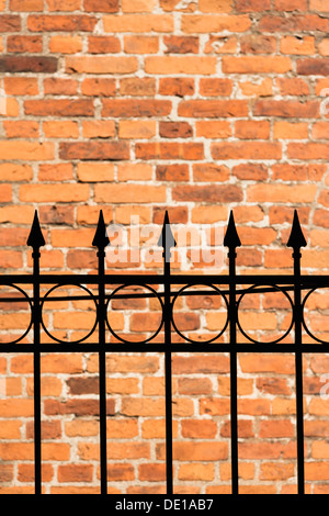 In mattoni rossi e parete nero ferro battuto recinzione Foto Stock