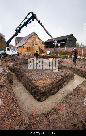 Auto costruzione di casa, fondazioni in calcestruzzo che viene colato e compattare il livello Foto Stock