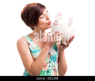 Bella donna felice baciando un salvadanaio, isolato su uno sfondo bianco Foto Stock