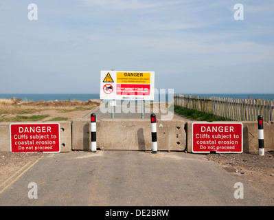 Cartelli di avvertimento su una strada chiusa da erosione costiera East Yorkshire Aldbrough Holderness England Regno Unito Foto Stock