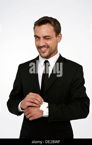 L uomo indossa una tuta tirando un asso di cuori al di fuori della sua manica Foto Stock