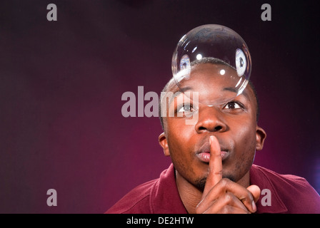 Di carnagione scura giovane con soap bubble, facendo un gesto di silenzio Foto Stock