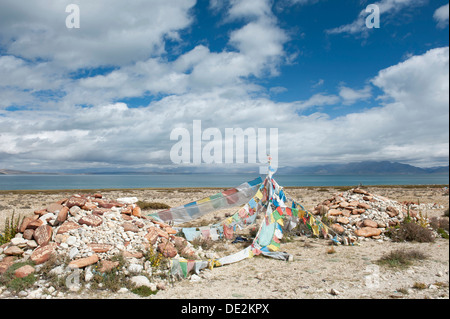 Buddismo tibetano, Mani pietre colorate e bandiere di preghiera con script tibetano, ex monastero di Gompa Nyengo sopra il lago Foto Stock