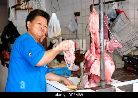 Femmina carattere cinese con una manciata di frattaglie prepara la carne di maiale in un negozio di macellaio in malang java indonesia Foto Stock