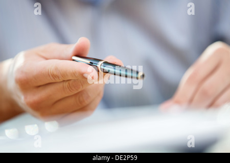 Mano d'uomo facendo gesto di accento o rivolti a qualcosa con una penna nera durante una riunione o negoziazione Foto Stock