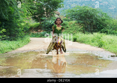 Rurale villaggio indiano Ragazza che corre attraverso una pozza di fango. Andhra Pradesh, India Foto Stock