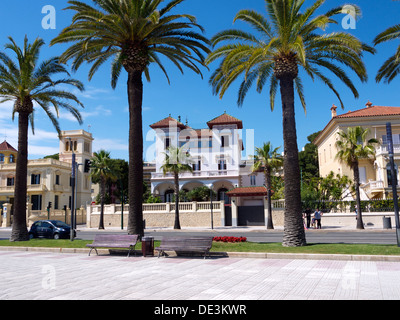 Palazzo spagnolo su una strada fiancheggiata da palme con un cielo blu Foto Stock