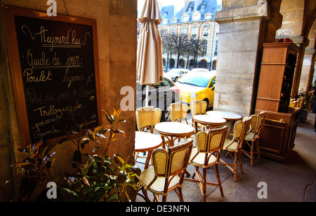 Parigi, Place de Vosges nel Marais - café sotto arcate con esso è allineato le tabelle e menu di bordo sul muro. Foto Stock