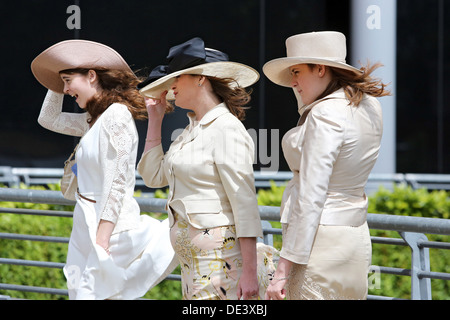 Ascot, Regno Unito, elegantemente vestito donne tenere in alta venti Huete loro fissato Foto Stock