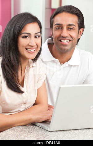 Asian Indian giovane, marito e moglie, uomo e donna, utilizzando il computer portatile in cucina a casa Foto Stock