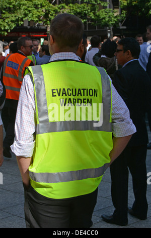 Close up di alta visibilità canottiera indossata da evacuazione operaio durante la pratica messa ufficio workforce drill incendio Foto Stock