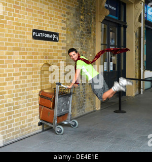 Il fan di Harry Potter ricrea spingendo un carrello verso il binario nove e tre quarti del film alla stazione ferroviaria di Kings Cross Londra Inghilterra Regno Unito Foto Stock