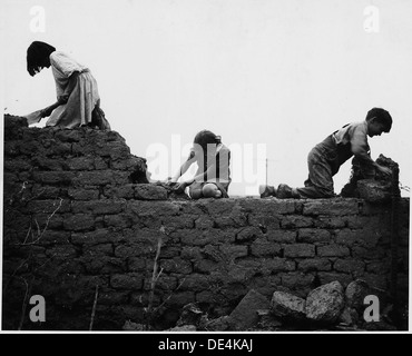 Taos County, Nuovo Messico. I bambini aiutano ad abbattere edificio abbandonato. 521987 Foto Stock