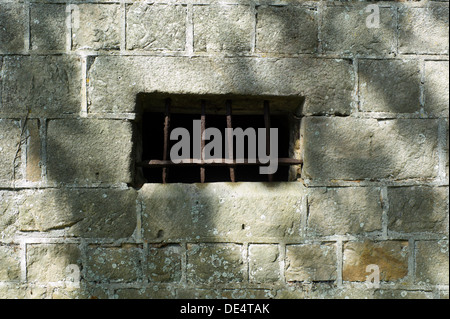 Finestra sbarrata, griglia in metallo, muro di pietra e le ombre Foto Stock
