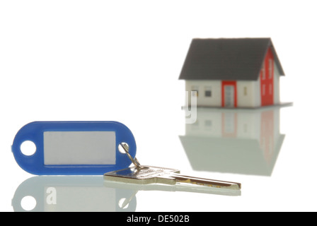 Il tasto disteso di fronte a una casa in miniatura, immagine simbolica per il mercato immobiliare Foto Stock