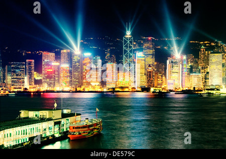 Isola di Hong Kong Cina skyline della città con la notte la luce laser show che si vede attraverso il Victoria Harbour da Kowloon Star Ferry Terminal Foto Stock