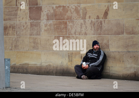 Un senzatetto mendica per denaro al lato della strada. Poveri squattrinati stranieri affamati barba Foto Stock