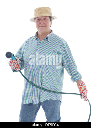 Senior giardiniere donna indossa cappello di paglia holding tubo da giardino su sfondo bianco Foto Stock