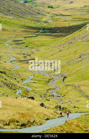 I ciclisti scendono ripidi lato ovest di Wrynose Pass nel Lake District inglese Foto Stock