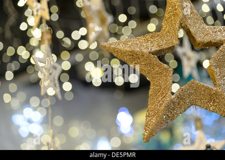 Oro metallizzato star ornamento di Natale sulla scintillante sfondo sfocato Foto Stock