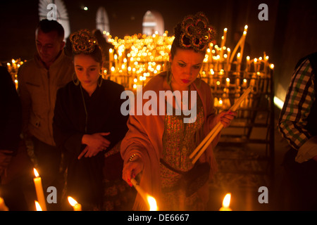 Una donna accende una candela nella camera votiva del santuario della Vergine del Rocio, in Almonte, parco nazionale di Donana Foto Stock