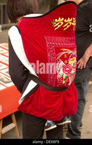 Cina bambino trasportato piggy-back nel mercato Foto Stock