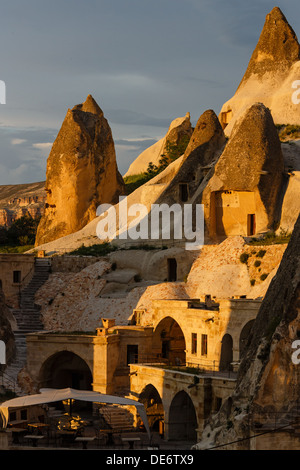 Camere Hotel tagliata nella roccia nella luce del sole al tramonto. Cappadocia, Turchia Foto Stock