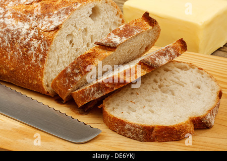 Appena a fette di pane e burro su di un tagliere con coltello Foto Stock