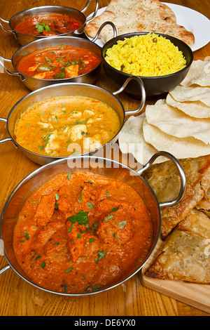 Selezione di curry indiano con riso pilaf, pane naan, poppadoms e samosa una popolare scelta nel buffet Foto Stock