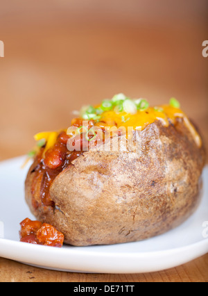 Caricato di patate al forno con peperoncino e formaggio su una piastra Foto Stock